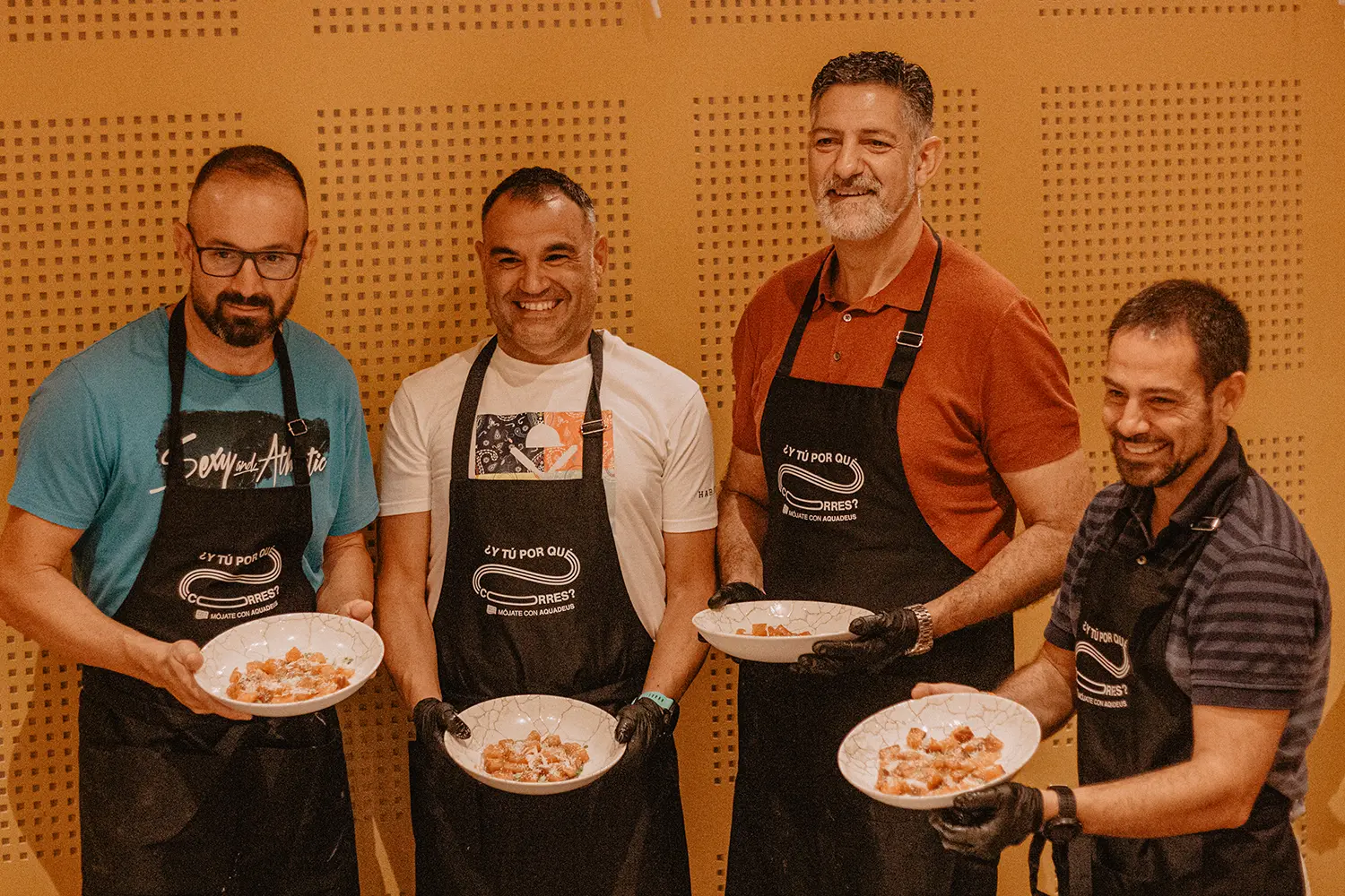 Algunos atletas de la Iniciativa Mójate con Aquadeus posan orgullosos con sus platos preparados durante el Teambuilding Saludable